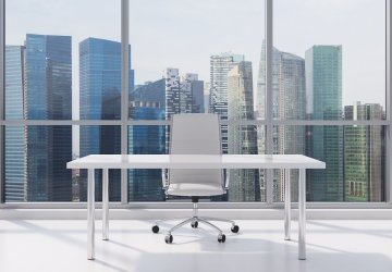 Office desk in front of a glass window in a business district.